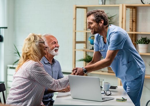 Happy Doctor Greeting Senior Couple Shaking Hands with Woman His Office